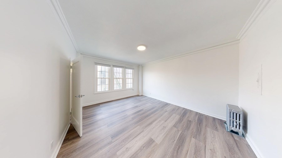A room with wooden flooring and a window with blinds.